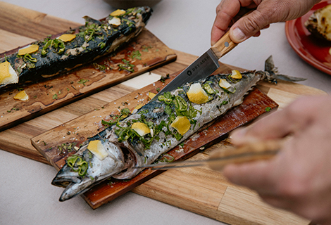 Ganzer Fisch wird auf einem Holzbrett angerichtet und für die Zubereitung vorbereitet.