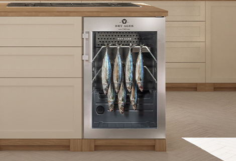Mehrere Fische reifen in einem eingebauten DRY AGER Reifeschrank in einer modernen Küche.